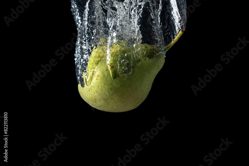 Fresh green pear in water splash isolated on black background. Minimal food concept.