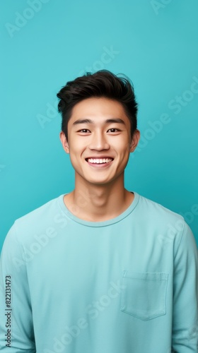 Teal Background Happy asian man realistic person portrait of young teenage beautiful Smiling boy good mood Isolated on Background ethnic diversity equality acceptance concept with copyspace