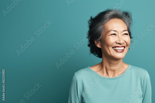 Teal Background Happy Asian Woman Portrait of Beautiful Older Mid Aged Mature Smiling Woman good mood Isolated Anti-aging Skin Care Face Beauty Product Banner with copyspace 