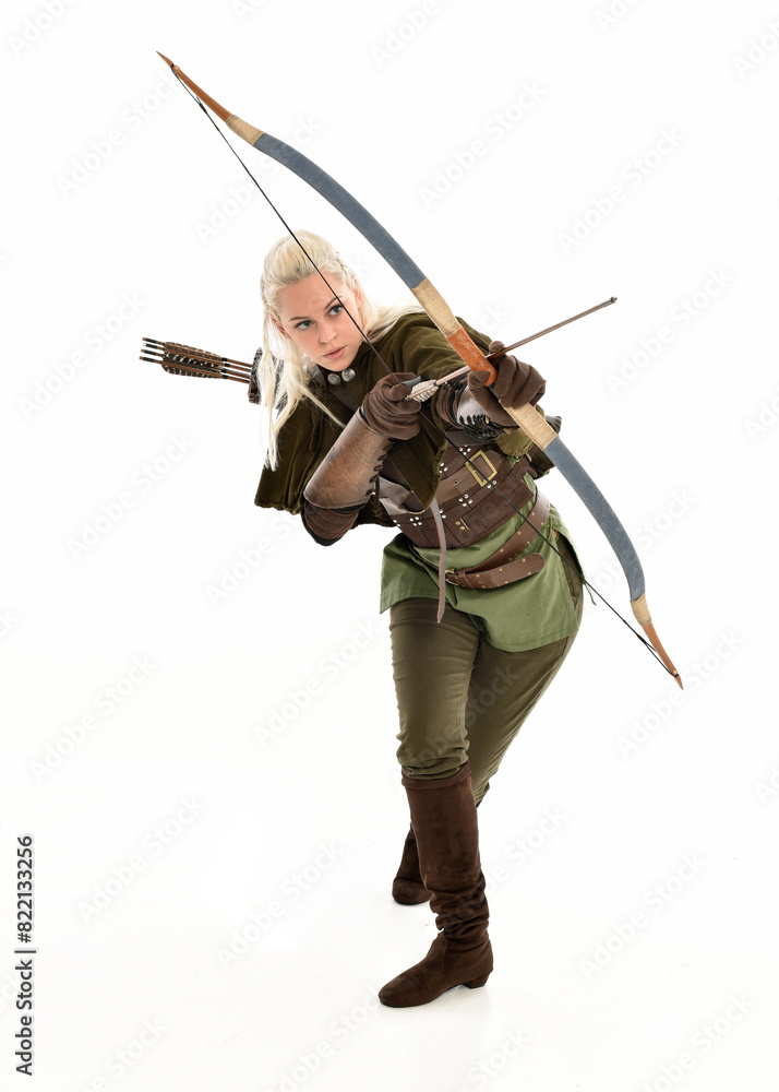 full length portrait of blonde female model wearing green fantasy elf warrior halloween costume with leather armour. standing pose, holding weapons. isolated on white studio background. full length portrait of blonde female model wearing green fantasy elf warrior halloween costume with leather armour. standing pose, holding weapons. isolated on white studio background.
