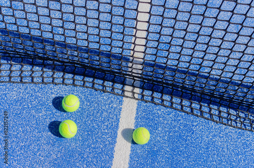 three balls near the net on a blue paddle tennis court
