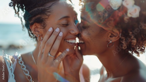 A beautiful lesbian couple exchanges rings and kisses beside the sea at an outdoor wedding ceremony. Gays share their Big Day with diverse multiethnic friends. LGBTQ relationship goals. photo