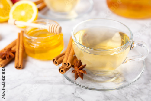 Fragrant hot tea with cinnamon stick and anise on a textured wooden background. A cup of hot tea with honey, lemon, mint and apples. Spicy tea with spices. Immunity tea. Health concept.Copy space.