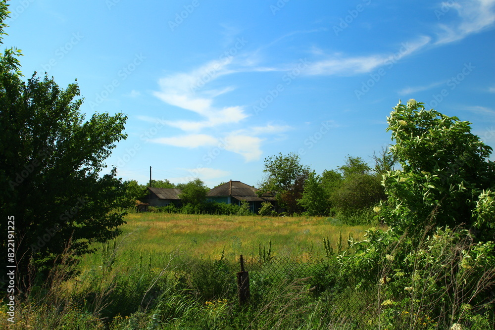 A grassy field with trees and buildings in the background A grassy field with trees and buildings in the background