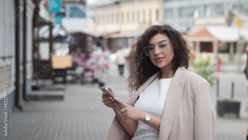 Beautiful business woman portrait in summer in the city with a phone in her hands