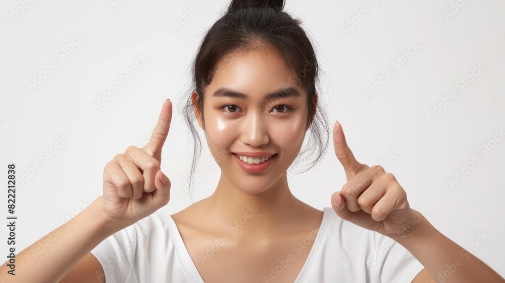 Asian woman smiling and pointing with two hands white background Asian woman smiling and pointing with two hands white background