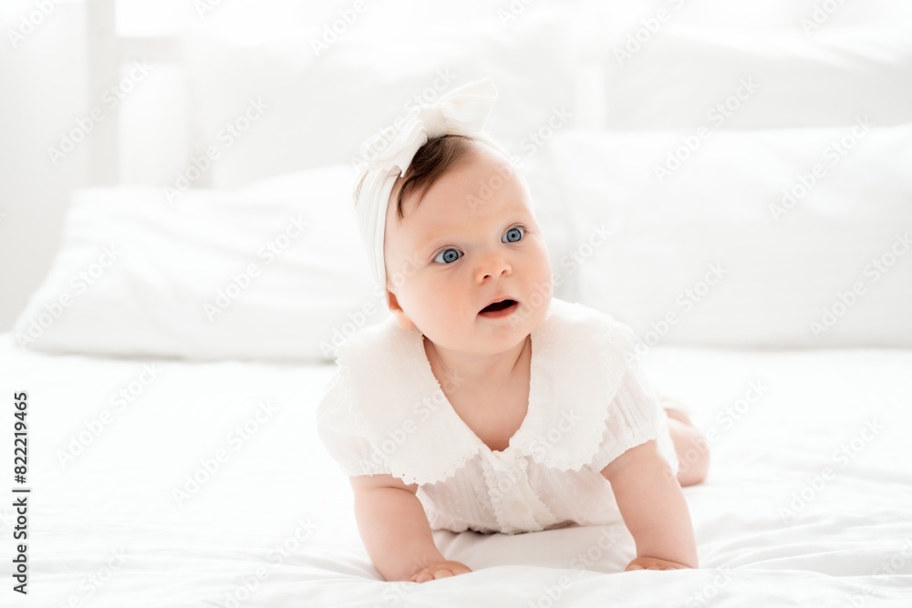 happy smiling newborn baby girl in white clothes on the bed at home, cute baby crawling, space for text happy smiling newborn baby girl in white clothes on the bed at home, cute baby crawling, space for text
