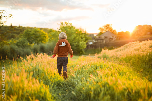 Wallpaper Mural A little baby running on the grass at sunset and enjoying life. A game of catch-up with a toddler. Fun and activities for children on the street. Happy childhood. Torontodigital.ca
