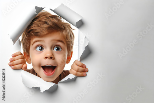 funny kid peeking out of hole in paper wall Isolated on white background photo
