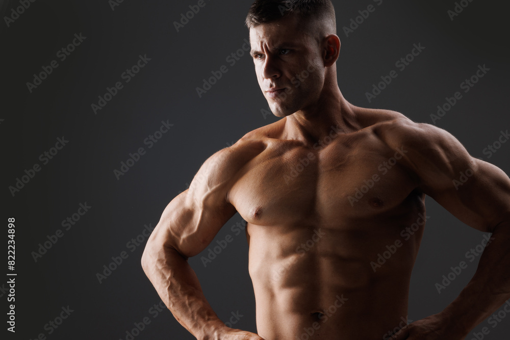 Muscular model sports young man on dark background. Fashion portrait of strong brutal guy. Male flexing his muscles. Muscular model sports young man on dark background. Fashion portrait of strong brutal guy. Male flexing his muscles.