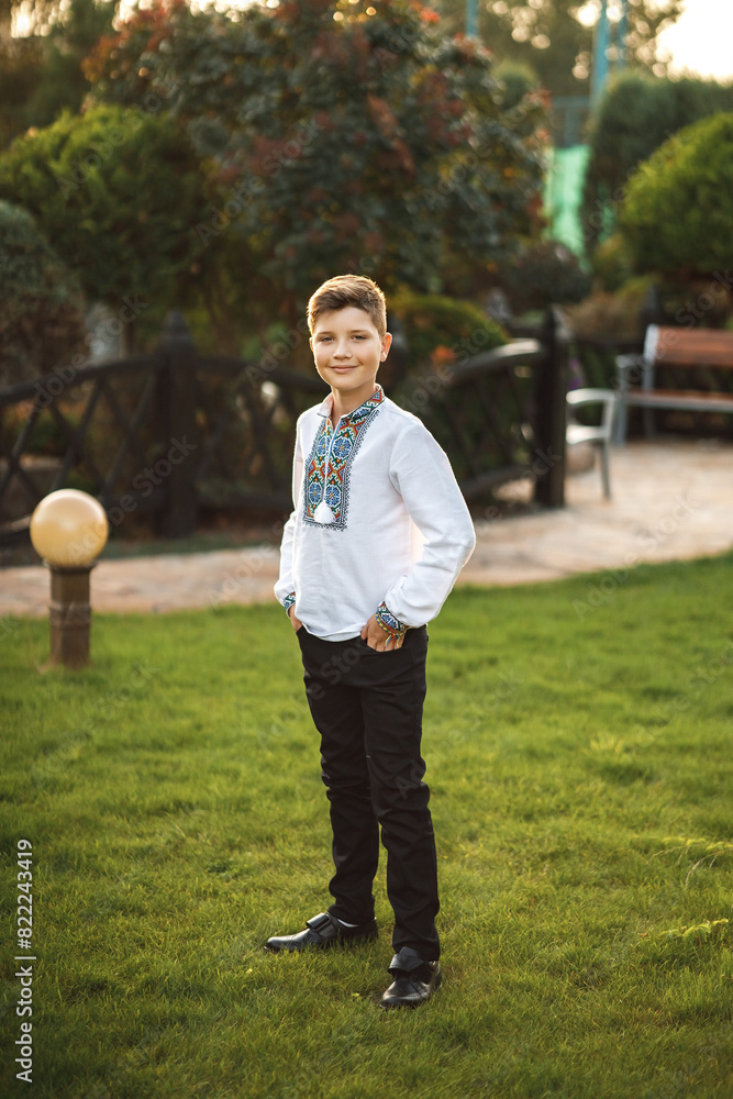Young teenager in an embroidered shirt posing in a summer park