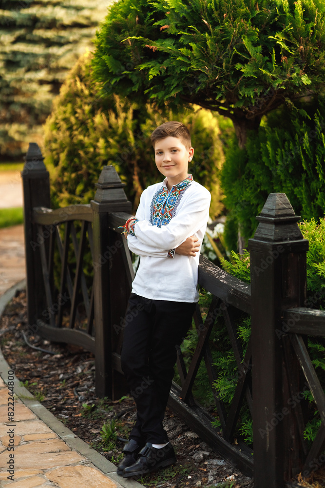 Young teenager in an embroidered shirt posing in a summer park