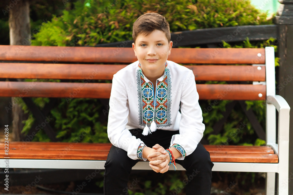 young teenager in an embroidered shirt sitting in the park