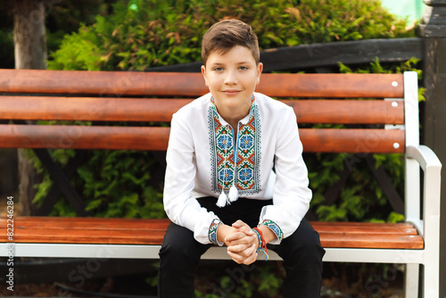 Obraz na płótnie young teenager in an embroidered shirt sitting in the park w salonie