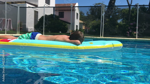 Child relaxing by the pool on inflatable mattress