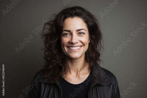 Portrait of a grinning woman in her 40s smiling at the camera in front of blank studio backdrop