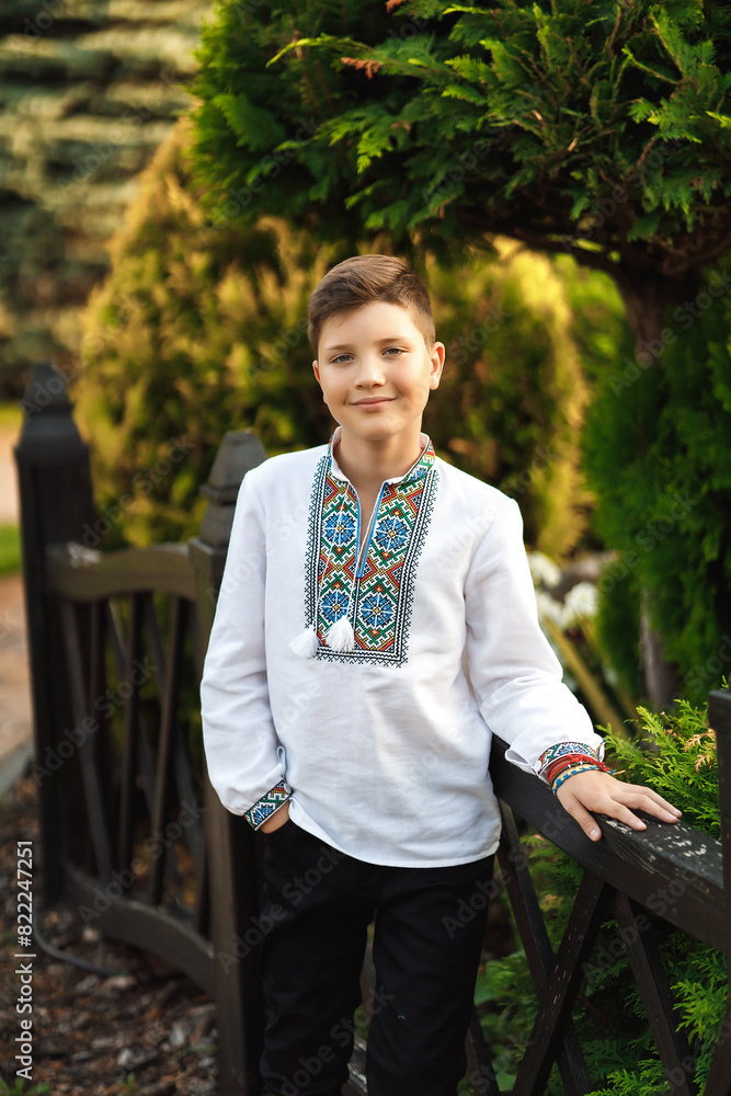 Young teenager in an embroidered shirt posing in a summer park