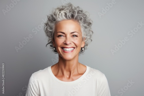 Portrait of a content woman in her 50s smiling at the camera in front of blank studio backdrop