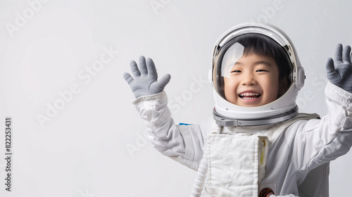 A cute happy smiling young Asian boy dresses like a astronaut on a plain white background with copy space for text.