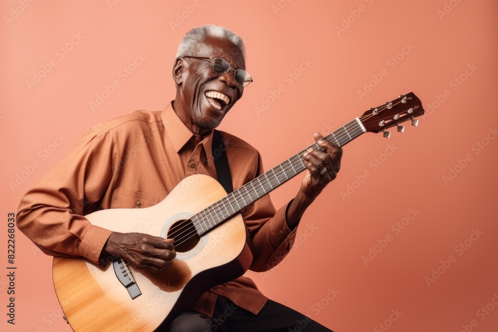Obraz premium Portrait of a content afro-american man in his 80s playing the guitar isolated on blank studio backdrop
