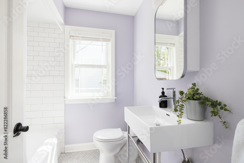 A bathroom with a shower pedestial sink  purple walls  and a shower with subway tiles.
