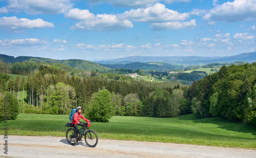 active senior woman on a bike packing tour with her electric mountain bike in the Bavarian Forest near Waldkirchen, Bavaria, Germany
