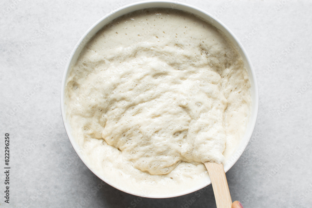 Overhead view of nigerian puff-puff dough that has proofed, puff-puff dough in a white mixing bowl, process of making puff-puff or bofrot