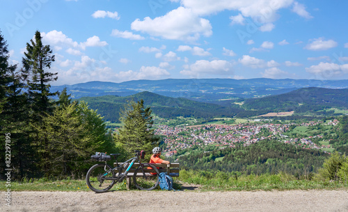 active senior woman on a bike packing tour with her electric mountain bikeup to the summit of Great Arber above village of  Bodenmais in the Bavarian Forest, Bavaria, Germany
