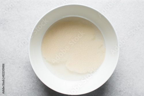 Instant dry yeast sprinkled on warm water, dry yeast granules on water photo