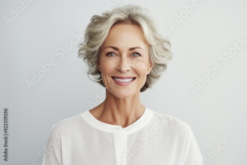 Portrait of a glad woman in her 50s smiling at the camera in front of plain white digital canvas