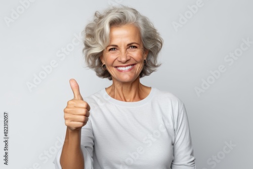 Wallpaper Mural Portrait of a smiling woman in her 50s showing a thumb up while standing against plain white digital canvas Torontodigital.ca