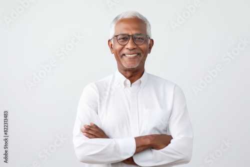 Portrait of a joyful indian man in his 70s with arms crossed isolated in plain white digital canvas © Markus Schröder