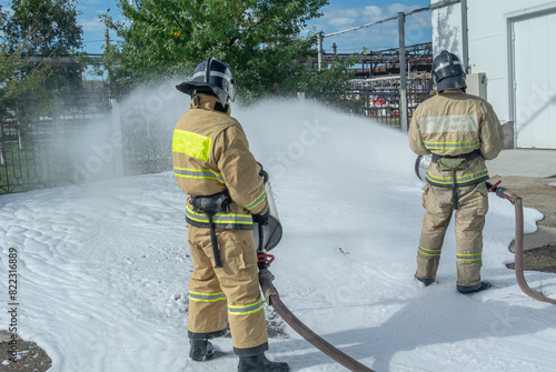 Firefighters in protective clothing with fire fighting equipment. Foam for extinguishing flammable liquids. The fire department. Firefighters extinguish the fire.