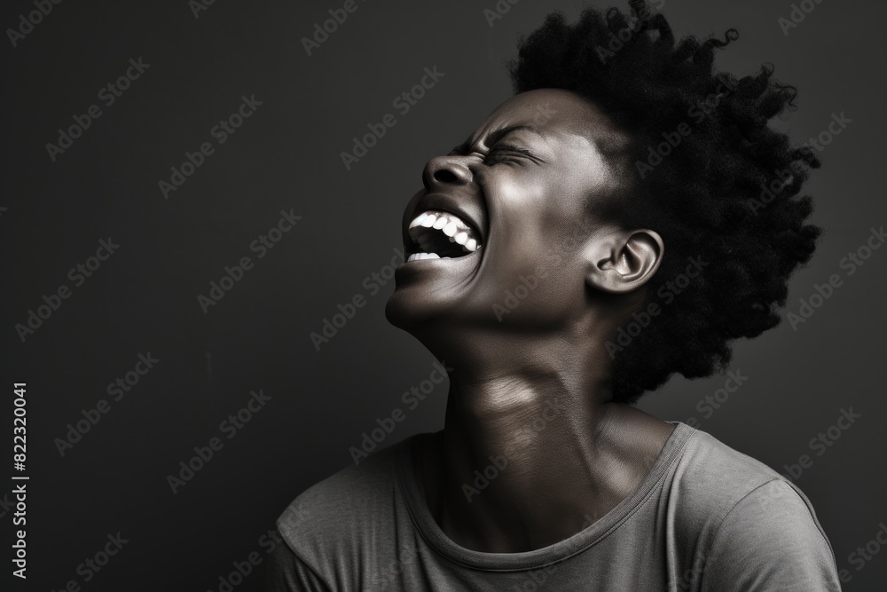 Portrait of a happy afro-american woman in her 40s laughing on bare monochromatic room