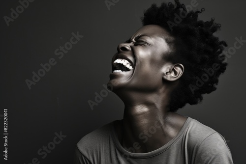 Portrait of a happy afro-american woman in her 40s laughing on bare monochromatic room