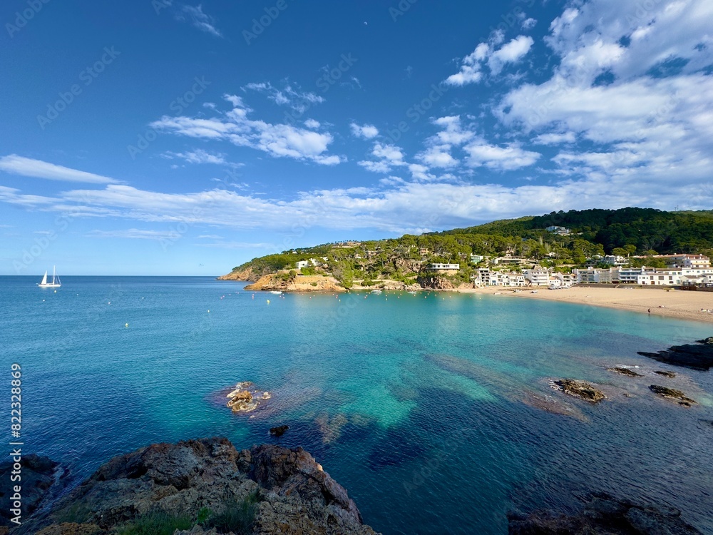 Fototapeta premium beautiful old houses, beach and turquoise colored water of the Mediterrane Sea in the bay of Sa Riera at a sunny day seen from the Camí de Ronda hiking trail, Costa Brava, Catalonia, Girona, Spain