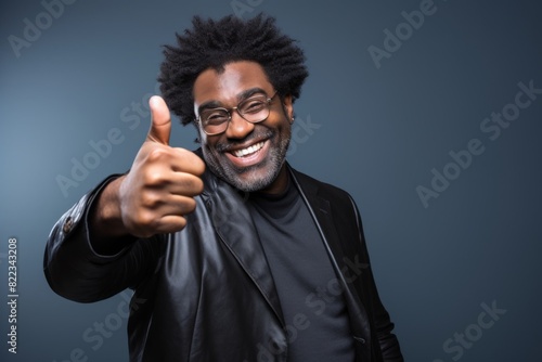 Portrait of a grinning afro-american man in his 40s showing a thumb up on plain cyclorama studio wall © Markus Schröder
