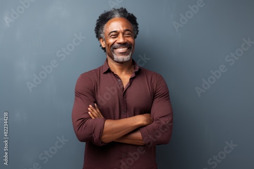 Portrait of a satisfied afro-american man in his 50s with arms crossed in plain cyclorama studio wall