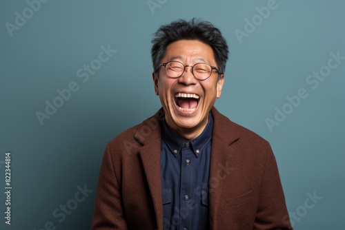 Portrait of a happy asian man in his 80s laughing in plain cyclorama studio wall