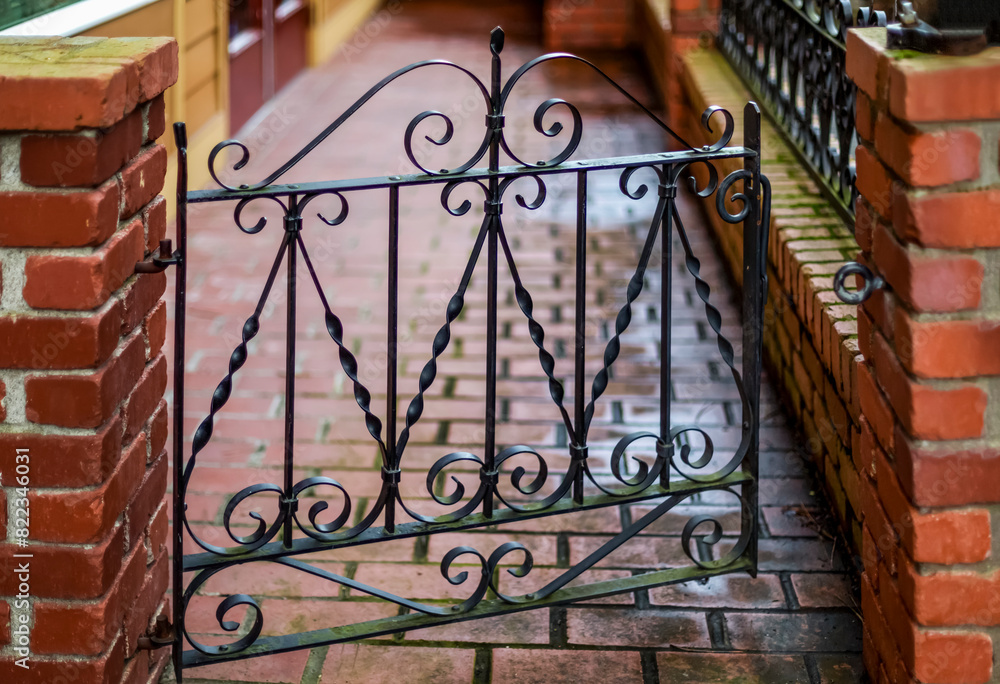 Wrought iron decorative gate slightly open between brick pillars; Fairhaven, Washington, United States of America Wrought iron decorative gate slightly open between brick pillars; Fairhaven, Washington, United States of America