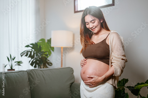 parenthood, pregnancy, family, motherhood, child, baby, pregnant, childbirth, prenatal, healthcare. A woman is pregnant and is smiling. She is wearing a brown top and a white sweater. Free Download parenthood, pregnancy, family, motherhood, child, baby, pregnant, childbirth, prenatal, healthcare. A woman is pregnant and is smiling. She is wearing a brown top and a white sweater. - GFXLoad