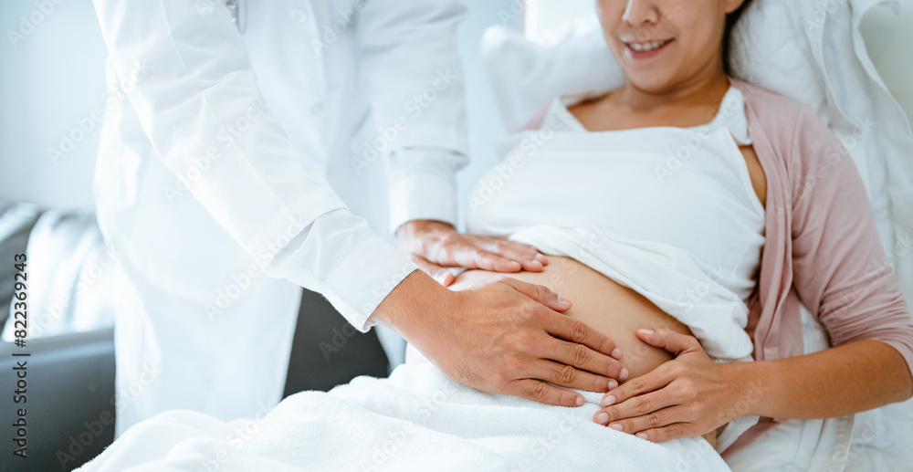 Obraz premium parent, parenthood, mother, pregnancy, motherhood, birth, pregnant, abdomen, tummy, anticipation. A woman is laying with doctor touching her stomach. doctor is checking on the baby inside.