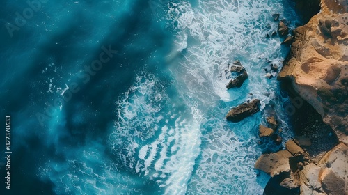 Aerial top view of sea, ocean blue waves crashing on rocky shore