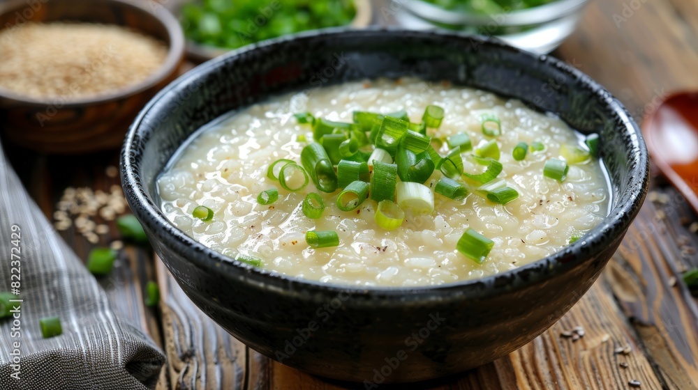 Elevated image of a bowl of rice porridge, garnished with green onions and served as a comforting breakfast dish. Elevated image of a bowl of rice porridge, garnished with green onions and served as a comforting breakfast dish.