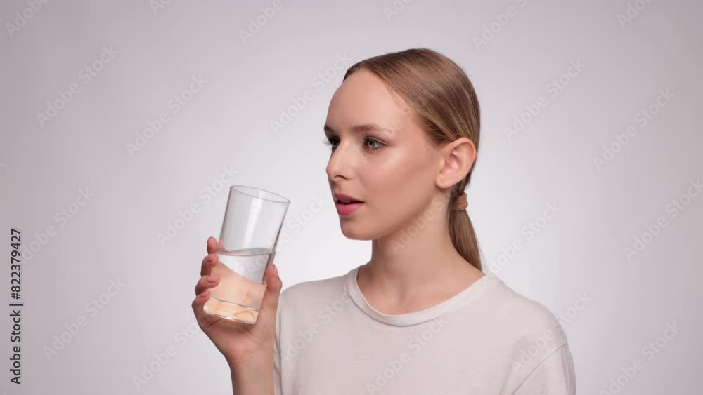 The girl drinks purified mineral water from a glass. The girl drinks purified mineral water from a glass.