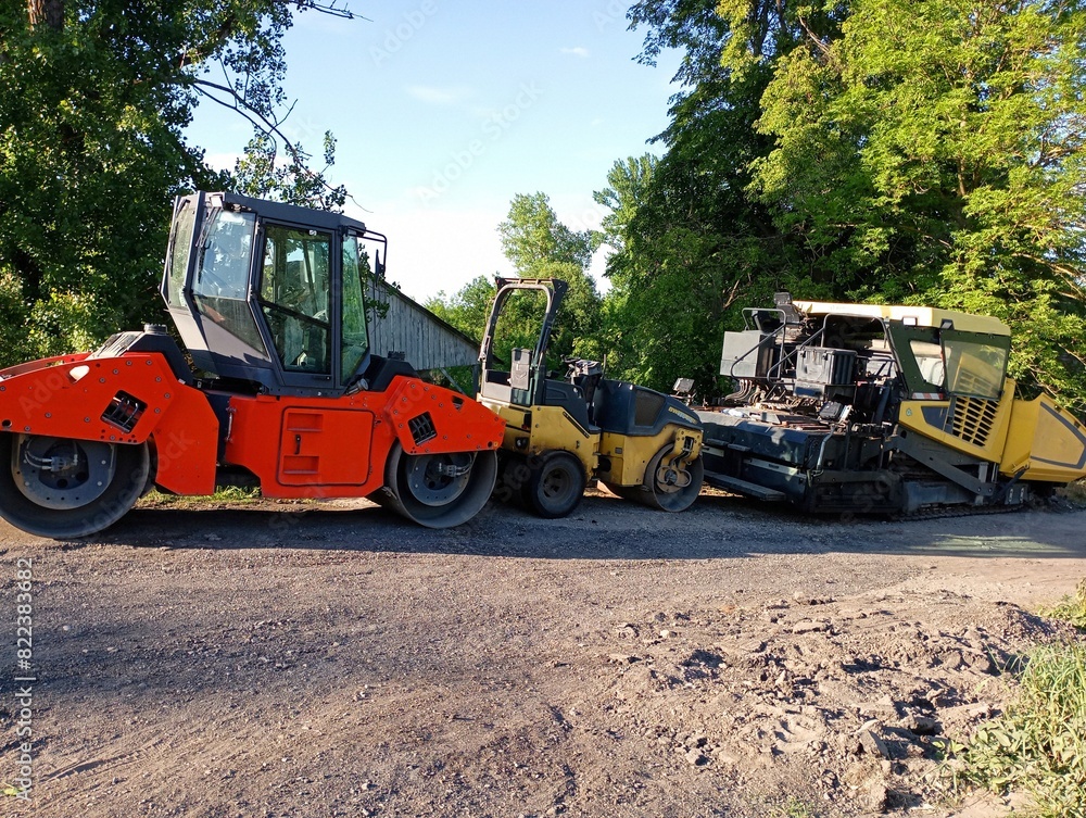Road repair equipment is parked on the side of the road. Road rollers and a machine for laying asphalt. Special automobile equipment for road surface repair. Road repair equipment is parked on the side of the road. Road rollers and a machine for laying asphalt. Special automobile equipment for road surface repair.
