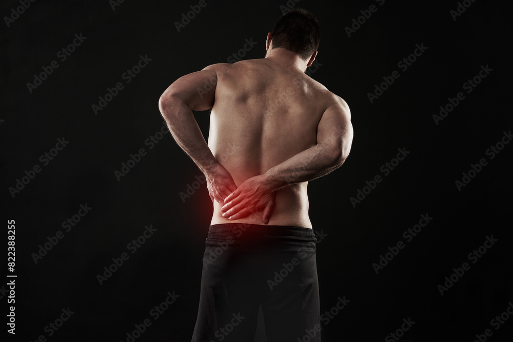Back pain, injury and red glow with man on black background for accident, anatomy or emergency. Fitness, healthcare and medical with shirtless athlete holding sore or stiff muscle in discomfort Back pain, injury and red glow with man on black background for accident, anatomy or emergency. Fitness, healthcare and medical with shirtless athlete holding sore or stiff muscle in discomfort