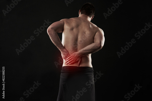 Back pain, injury and red glow with man on black background for accident, anatomy or emergency. Fitness, healthcare and medical with shirtless athlete holding sore or stiff muscle in discomfort