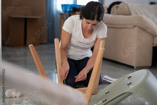 Foto Real photo of a woman at home assembling chairs she received by mail, gluing the