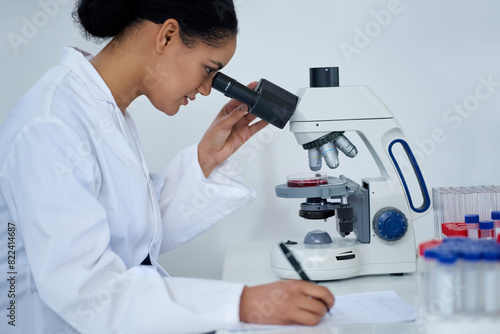 Woman, science and microscope for research, notes or dna blood analysis in lab. Scientist, microbiology and test on medical equipment, chemistry or writing biotechnology study for health innovation
